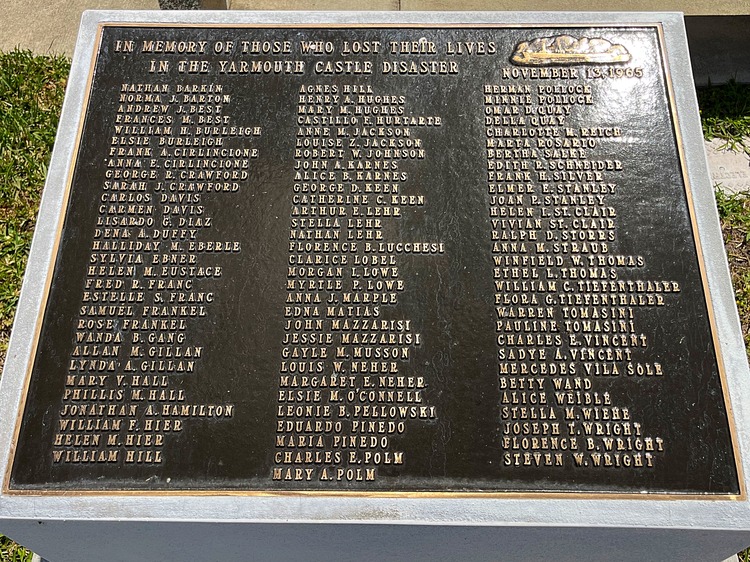 A picture of a bronze plaque with 91 names on it.