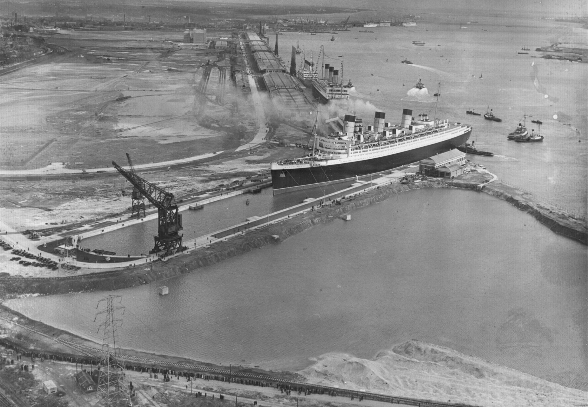 A black and white photo of a ship with three funnels going into drydock.