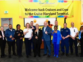 A group of people standing in front of a yellow banner that reads "Welcome back Cruisers and Crew to the Cruise Maryland Terminal."