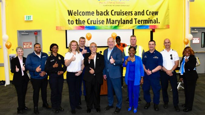 A group of people standing in front of a yellow banner that reads "Welcome back Cruisers and Crew to the Cruise Maryland Terminal."