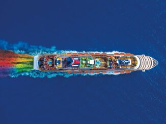 An aerial view of a cruise ship sailing with a rainbow wake.