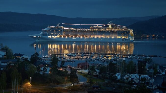 A brilliantly lighted cruise ship sailing at night.