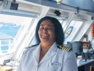 An image of a woman smiling in a white ship captain's uniform.