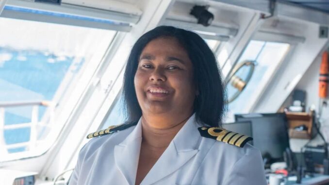 An image of a woman smiling in a white ship captain's uniform.