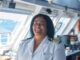 An image of a woman smiling in a white ship captain's uniform.