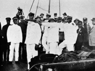 A group of uniformed men stand on the deck of a ship.