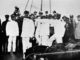 A group of uniformed men stand on the deck of a ship.