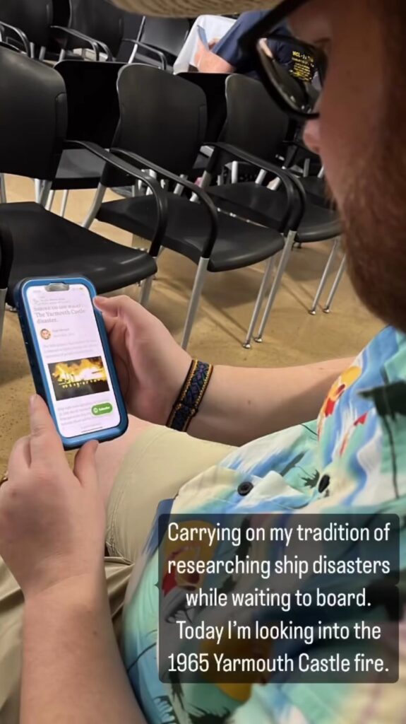 A man in a Hawaiian shirt looks a phone.