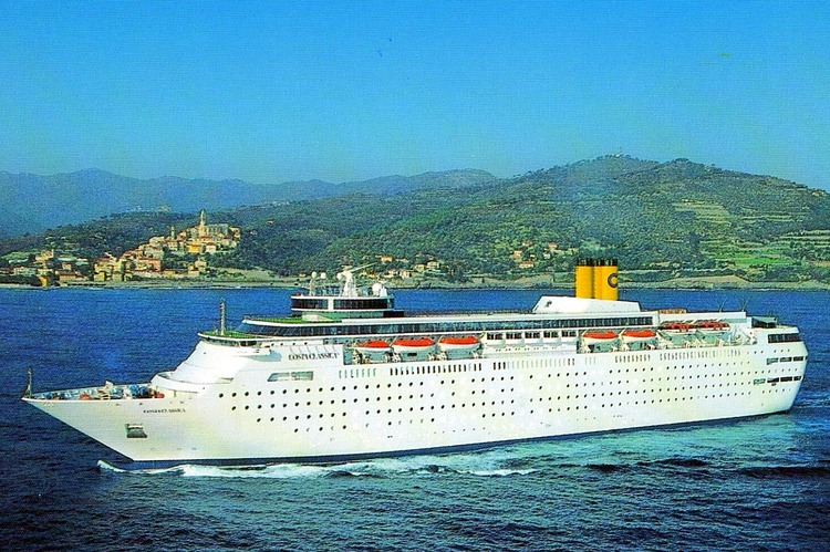 A picture of a cruise ship painted white. It has three yellow funnels with a blue C painted on each one.