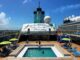 The pool deck of a cruise ship. There is a sign that reads "Margaritaville at Sea Paradise."