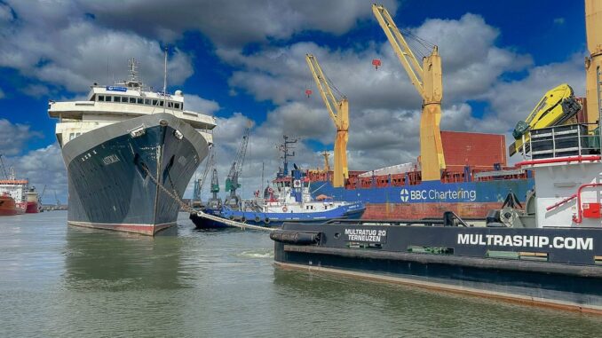 An image of an old cruise ship being towed out of a harbor.
