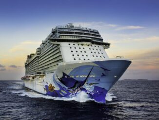 A big cruise ship with white paint and artwork featuring marine life on its hull.