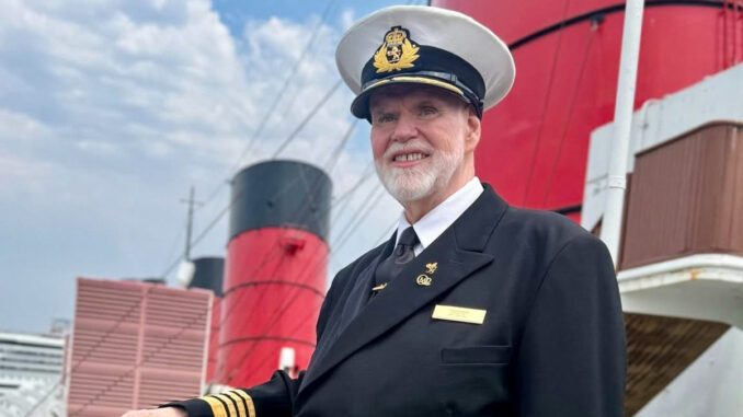 A photo of a uniformed man with a white beard standing in front of three red funnels.