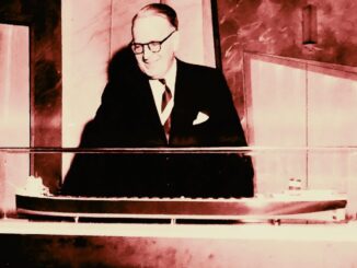 A man in a suit and tie looks at a model of a freighter.